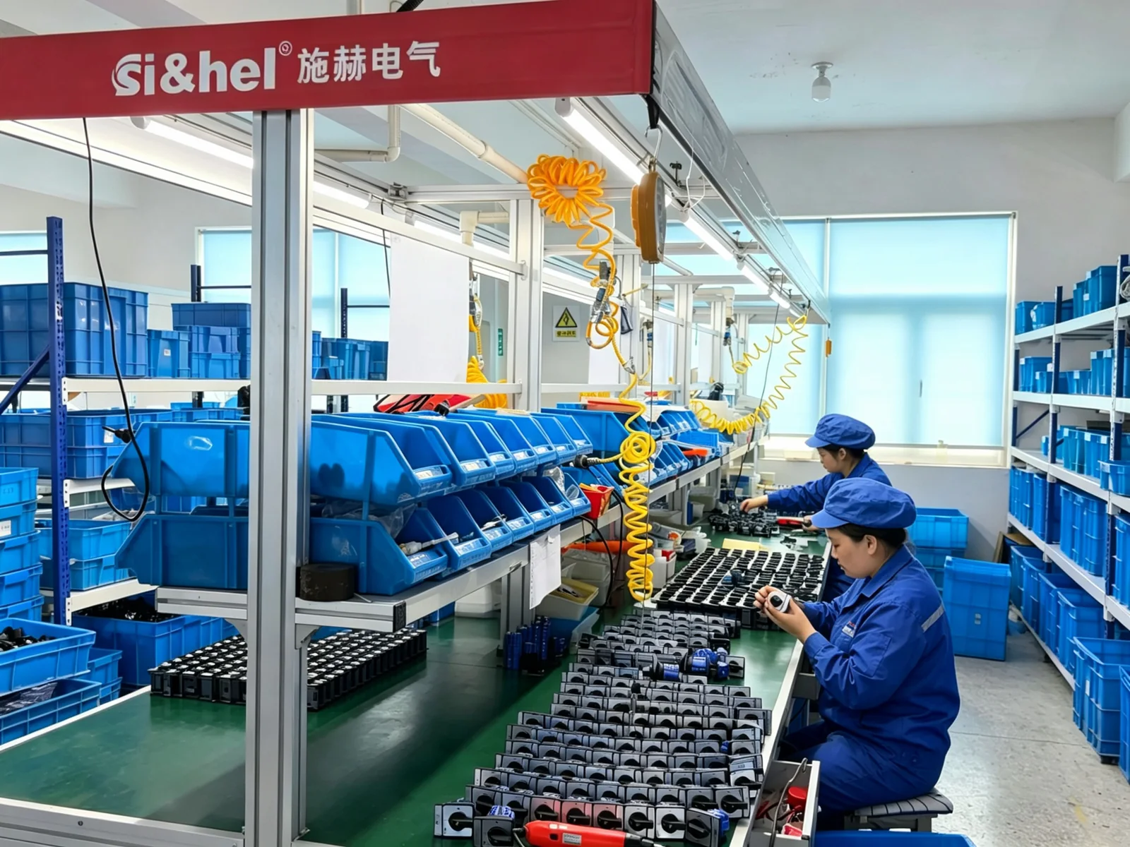 Operators assembling rotary switch components at a Shieldhz factory workstation