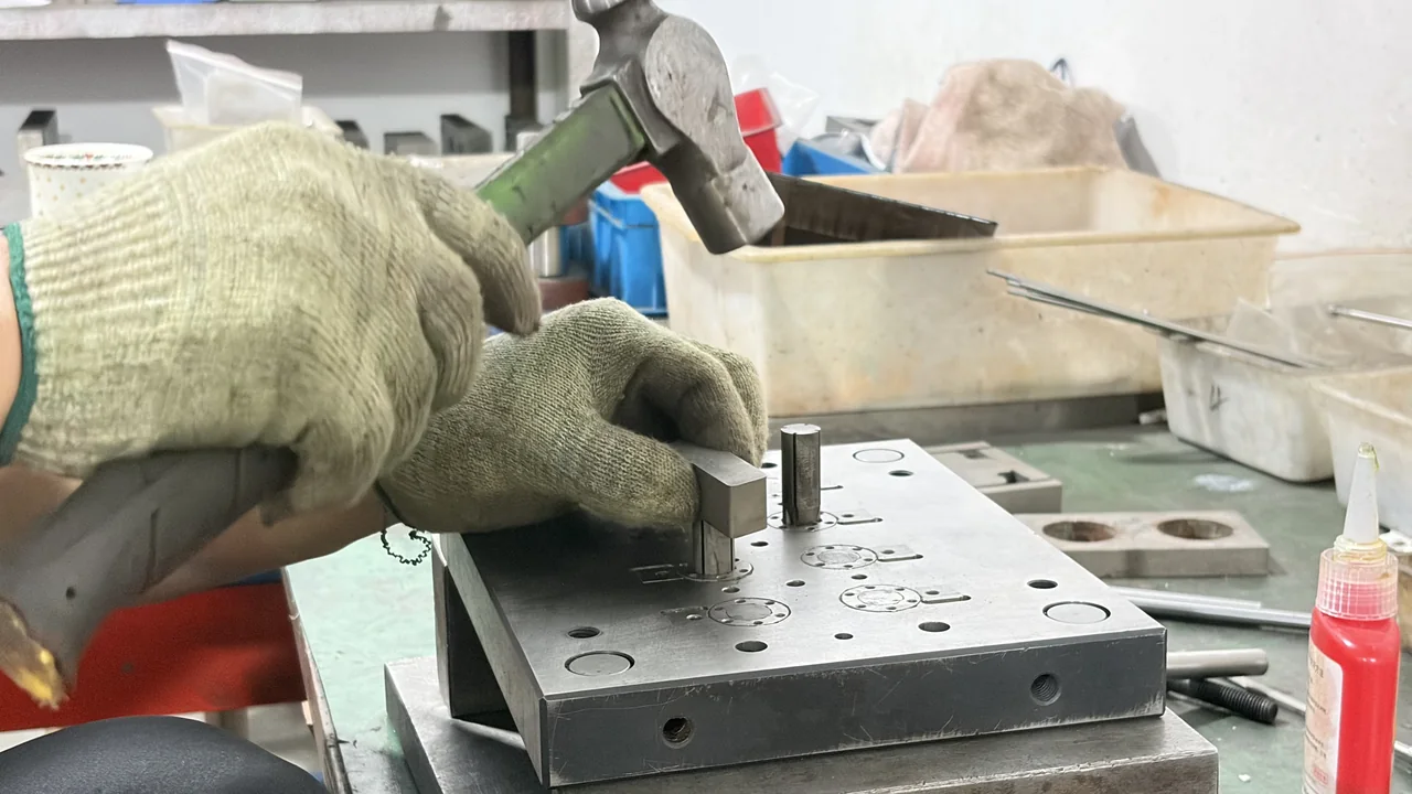 Gloved operator adjusting a switch mold at a tooling bench